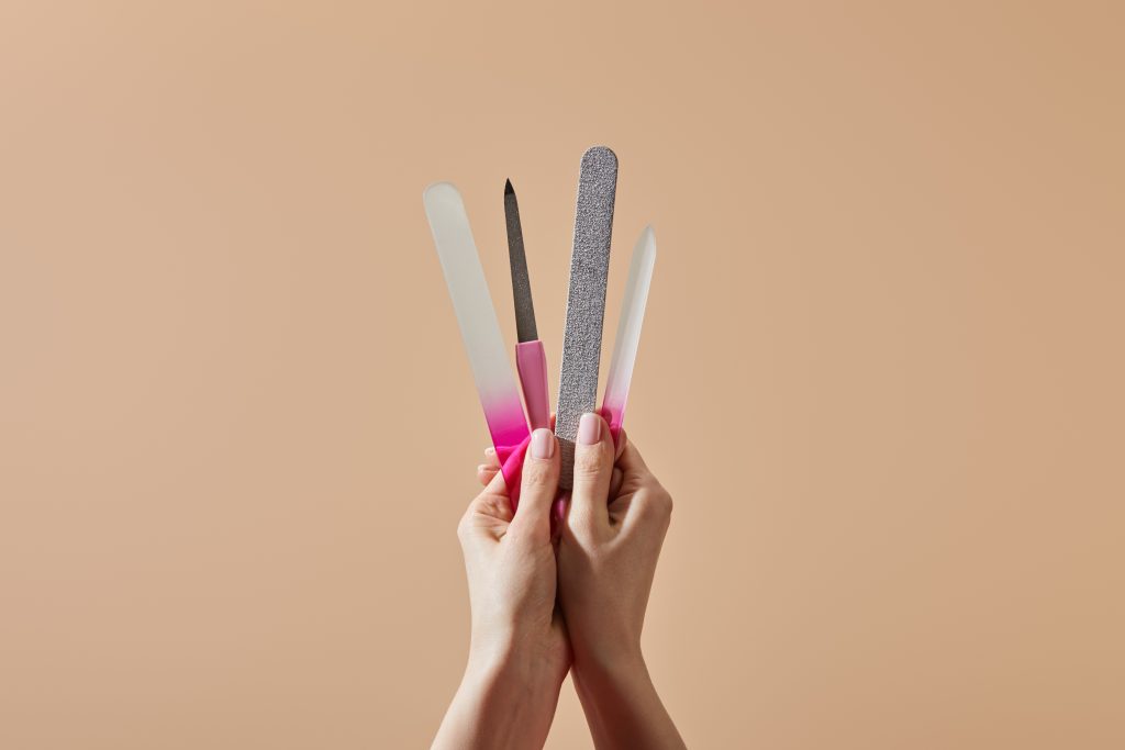 Cropped view of woman holding nail files and emery board isolated on beige. Nail File Types