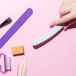 Woman aligns her nails with a nail file. Alignment of the nail edge. Manicure at home for yourself. A woman's hand with healthy natural nails. procedure of nail care. Top view