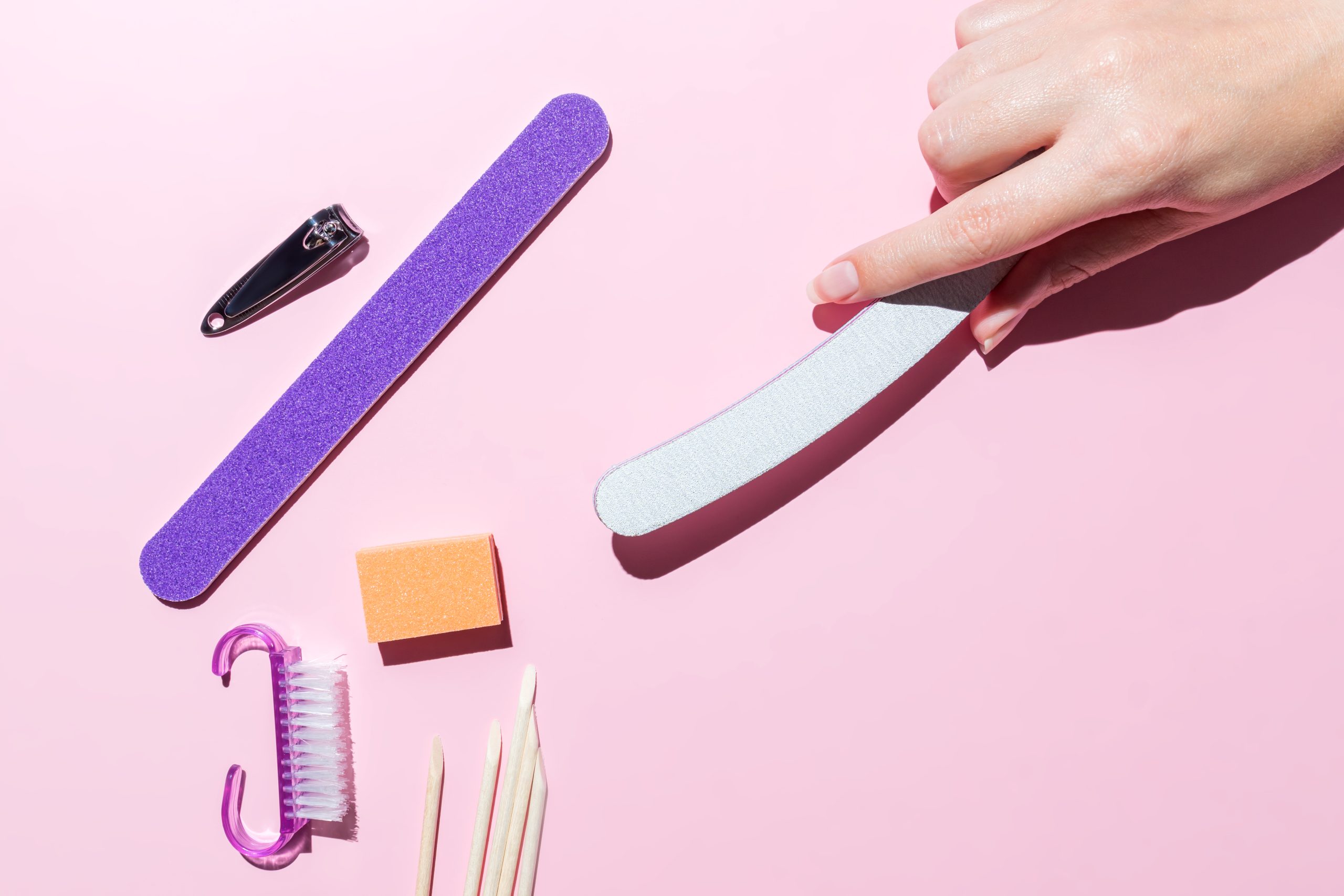 Woman aligns her nails with a nail file. Alignment of the nail edge. Manicure at home for yourself. A woman's hand with healthy natural nails. procedure of nail care. Top view