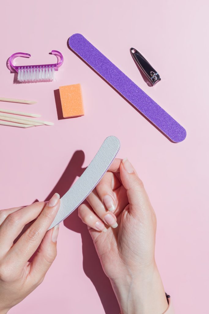 Woman aligns her nails with a nail file. Alignment of the nail edge. Manicure at home for yourself. A woman's hand with healthy natural nails. procedure of nail care. Top view