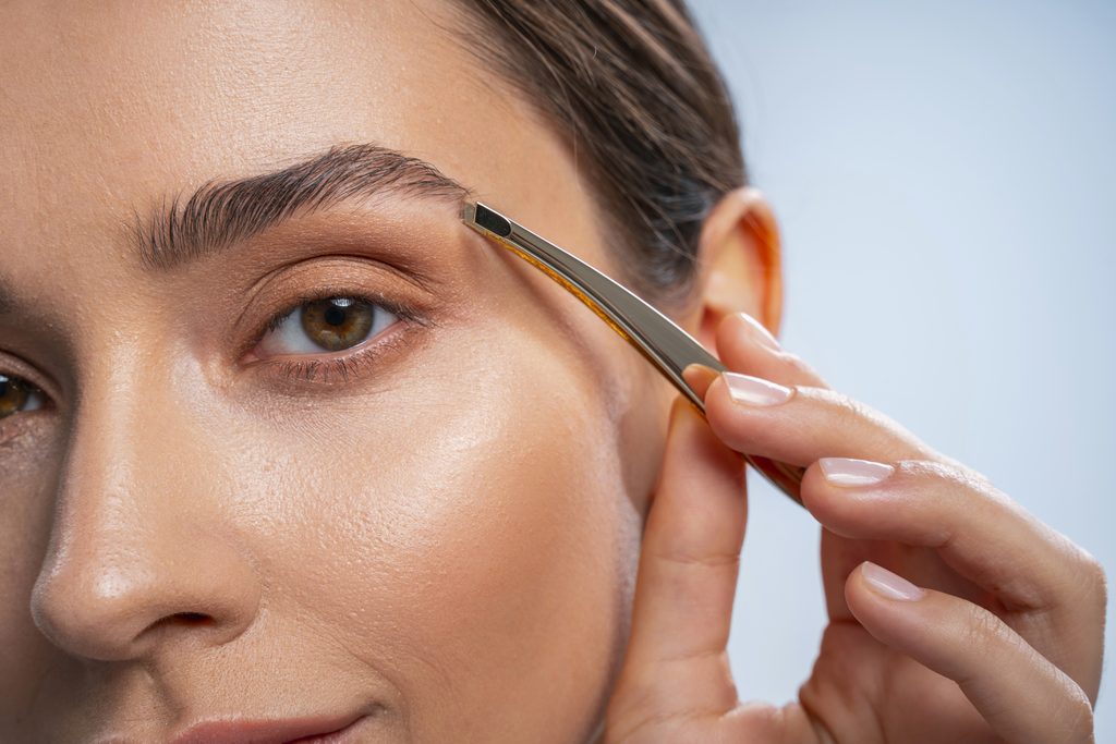 Well done. Beautiful girl staring at camera while doing eyebrows correction. Tint Eyebrows at Home.