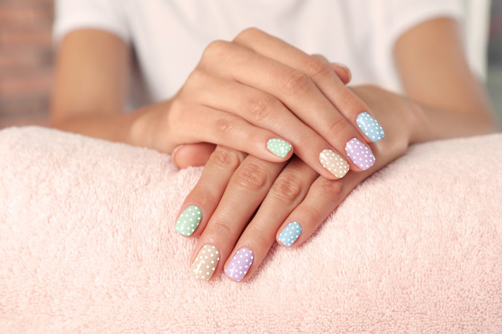 Woman showing her stylish colorful manicure. She holding hands on towel, closeup