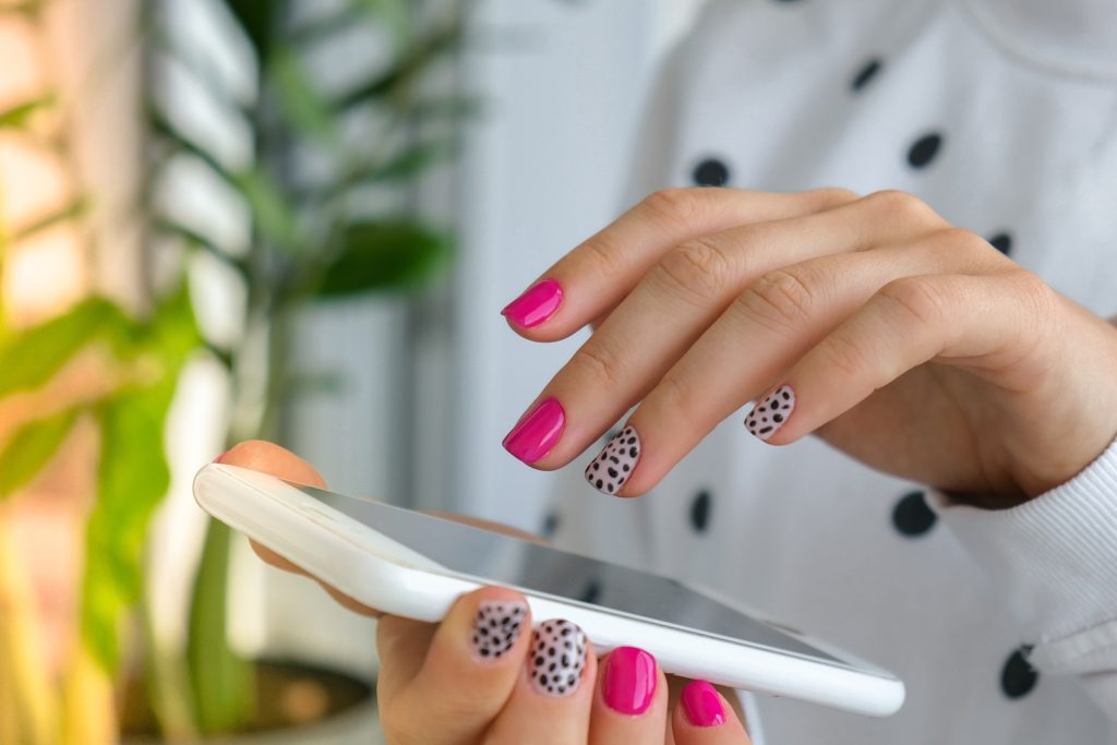 Woman with polka dot and pink nails using iphone