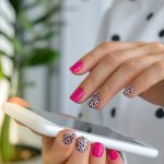 Woman with polka dot and pink nails using iphone